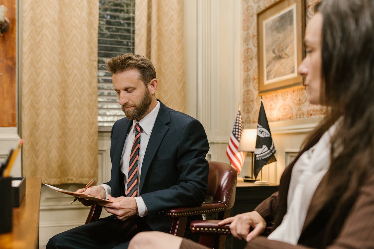 A lawyer in business attire reviewing documents during a meeting in an office.